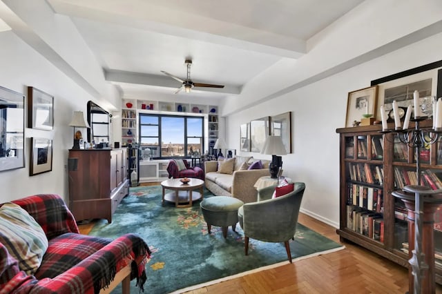 living area with a ceiling fan, beamed ceiling, and baseboards