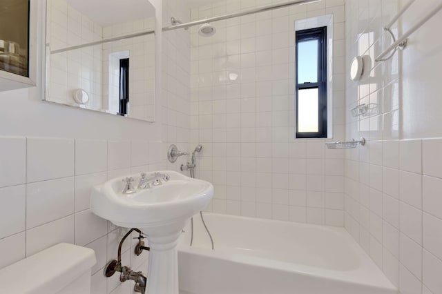 bathroom featuring toilet, tub / shower combination, and tile walls