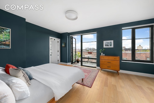 bedroom with light wood finished floors, baseboards, and access to outside