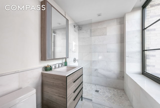 bathroom with vanity, tile walls, walk in shower, and toilet