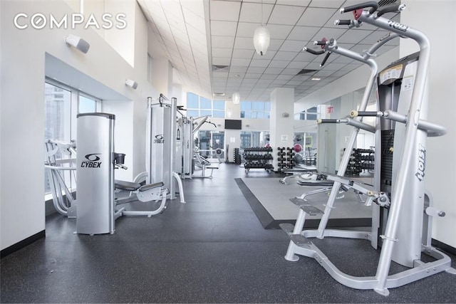 exercise room with a drop ceiling and baseboards