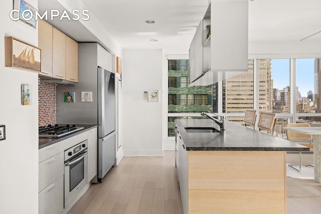 kitchen with a city view, stainless steel appliances, a sink, backsplash, and modern cabinets