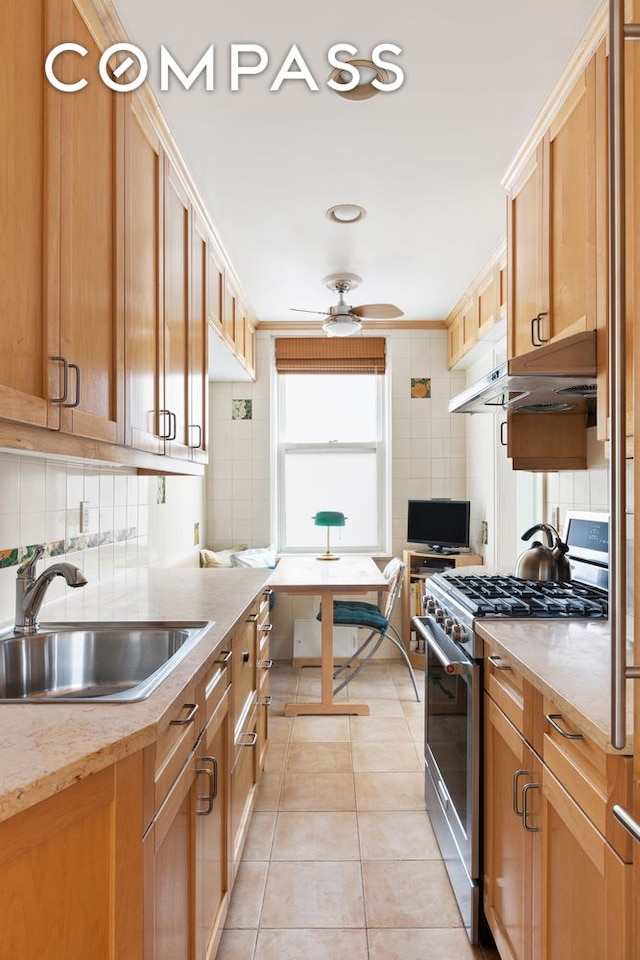 kitchen featuring light tile patterned floors, light countertops, decorative backsplash, stainless steel range with gas stovetop, and a sink