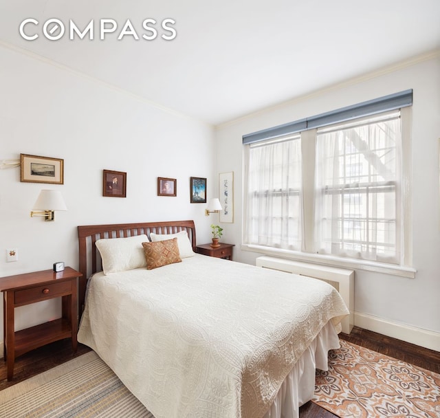 bedroom with ornamental molding, baseboards, and wood finished floors