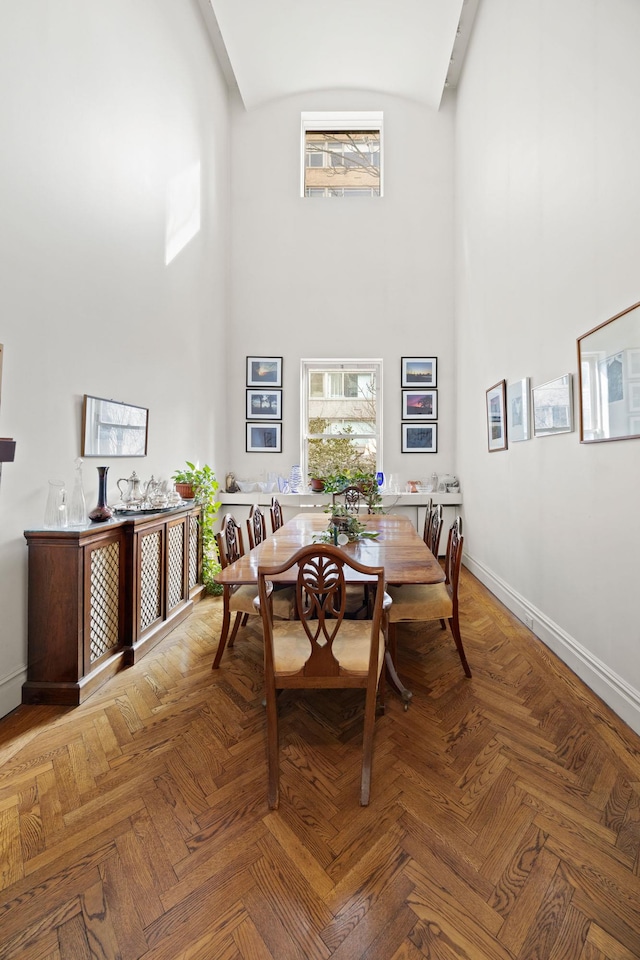 dining space featuring a towering ceiling and baseboards