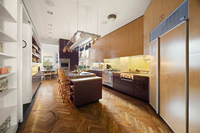 kitchen featuring a breakfast bar, hanging light fixtures, backsplash, a kitchen island with sink, and high quality appliances