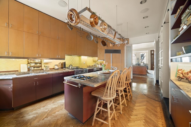 kitchen with a breakfast bar, backsplash, a sink, and light stone countertops