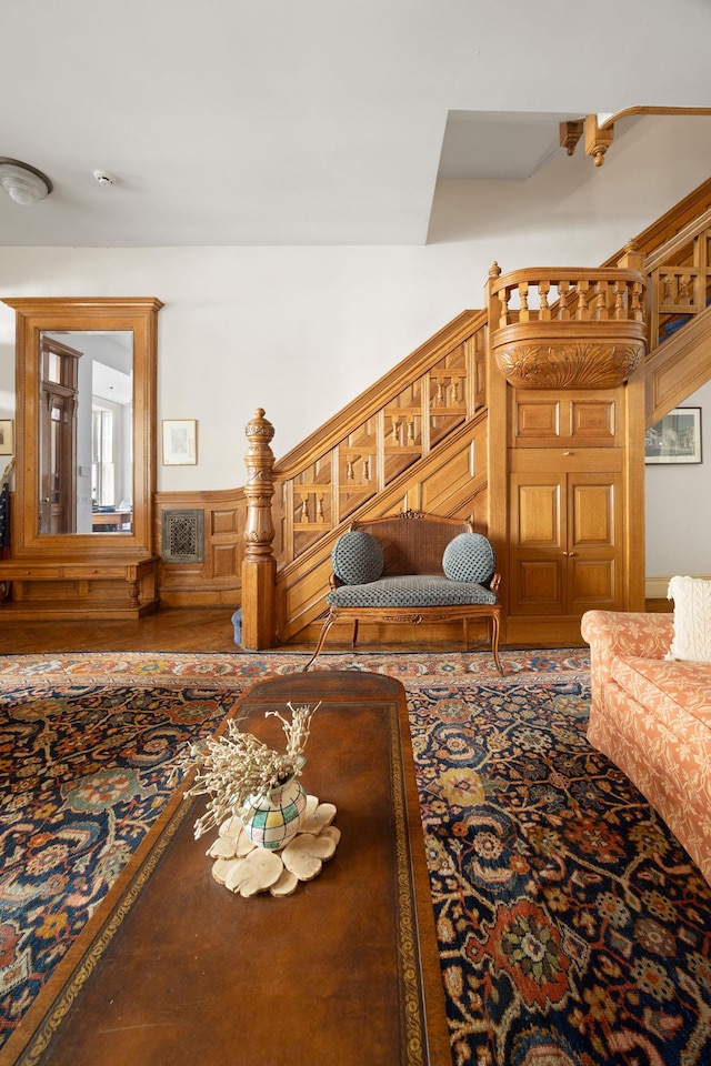 living area featuring a wainscoted wall, stairway, and visible vents