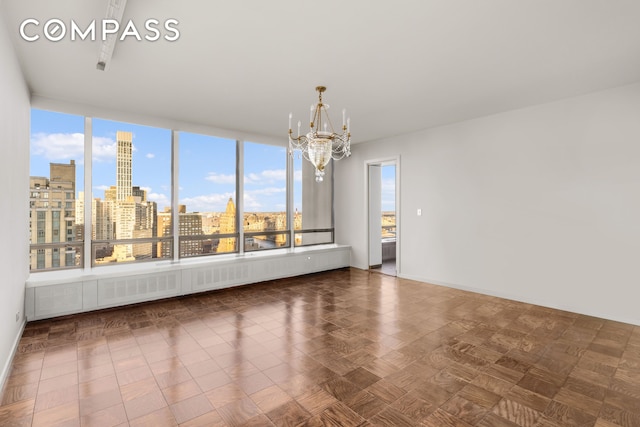 unfurnished room featuring baseboards, an inviting chandelier, and a city view