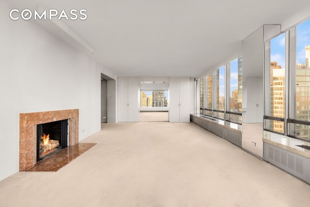 unfurnished living room with carpet floors, radiator heating unit, a city view, and a high end fireplace