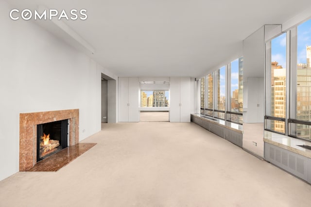 unfurnished living room featuring a fireplace, a city view, carpet floors, and plenty of natural light