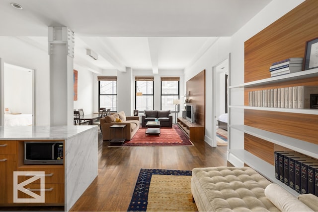 living room with beam ceiling and dark wood-style floors