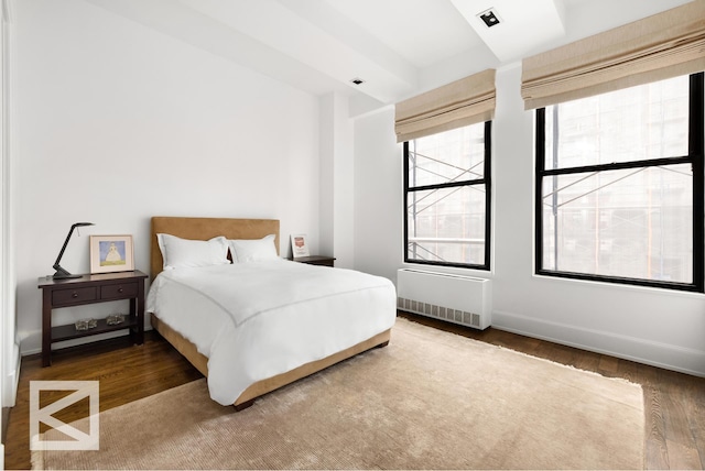bedroom with wood finished floors, baseboards, and radiator heating unit