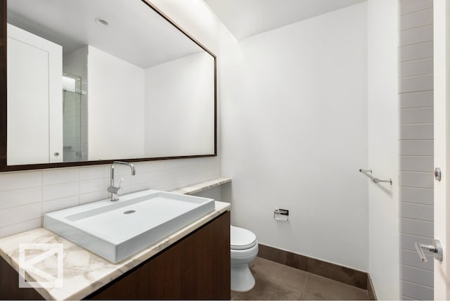 bathroom featuring decorative backsplash, toilet, vanity, baseboards, and tile patterned floors