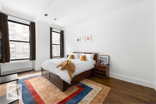 bedroom with radiator, baseboards, and wood finished floors