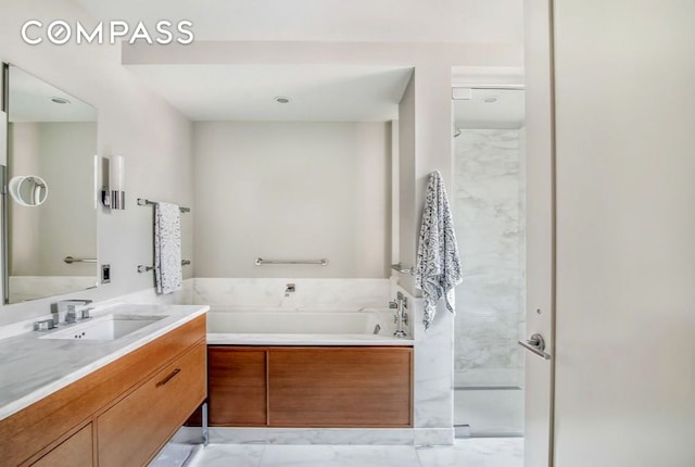 bathroom with a garden tub, marble finish floor, and vanity