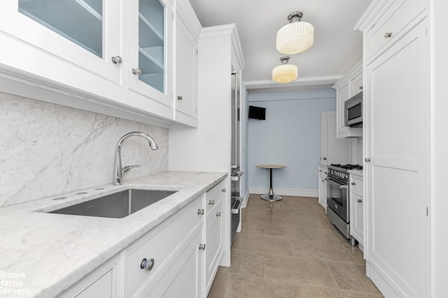 kitchen with stainless steel appliances, a sink, white cabinetry, decorative backsplash, and glass insert cabinets