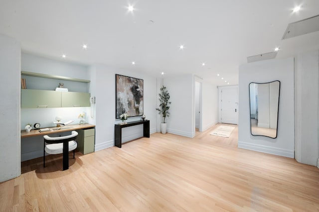 kitchen with recessed lighting, baseboards, light wood-style floors, built in desk, and green cabinetry