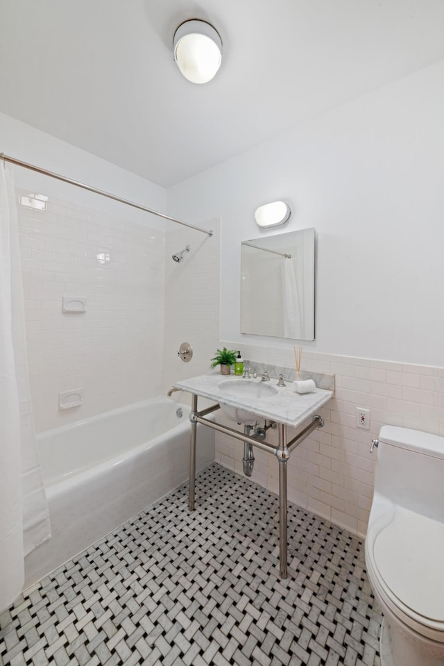 bathroom featuring shower / bath combo, toilet, a wainscoted wall, tile patterned flooring, and tile walls