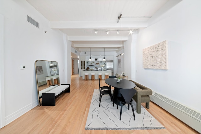 dining area featuring visible vents, light wood-style flooring, a baseboard radiator, and beam ceiling