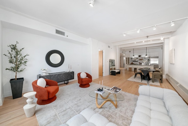 living room featuring light wood-type flooring, visible vents, and baseboards