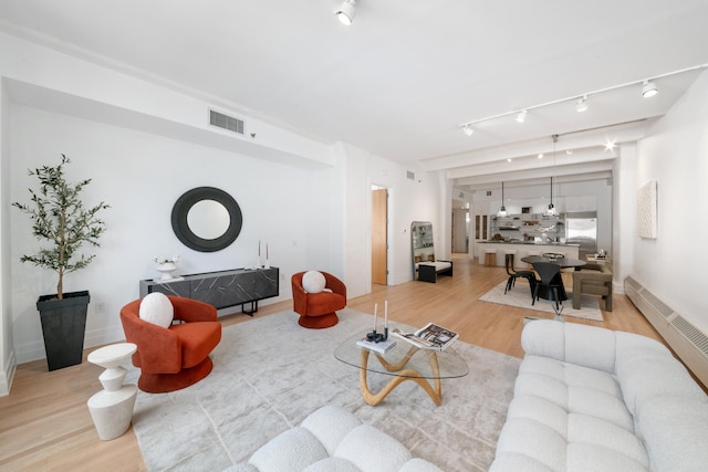 living room with baseboards, rail lighting, light wood-style flooring, and visible vents