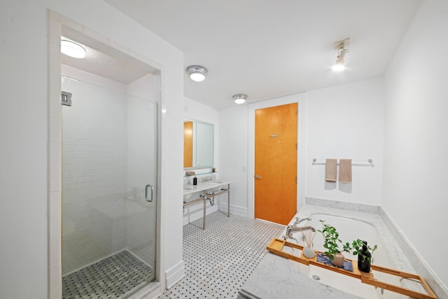 full bathroom with a stall shower, a garden tub, vanity, and baseboards