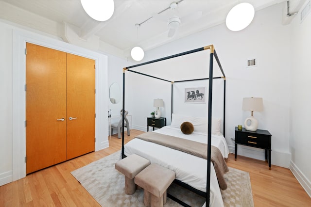 bedroom featuring baseboards, visible vents, beam ceiling, and light wood-type flooring