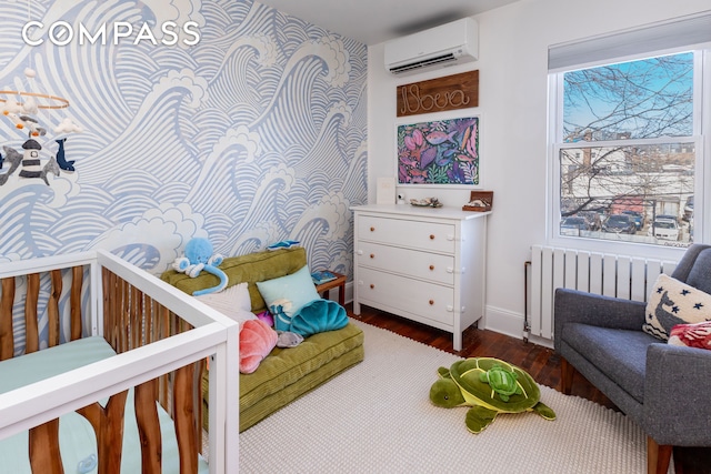 bedroom with radiator, a wall mounted air conditioner, baseboards, and wood finished floors