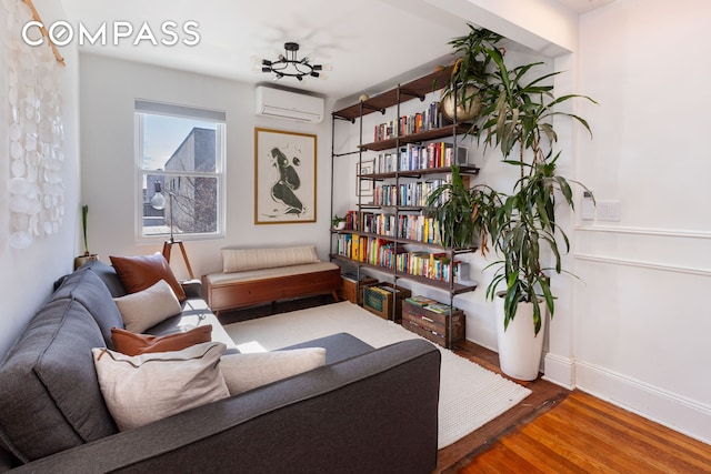 sitting room featuring a wall mounted AC, wood finished floors, and baseboards