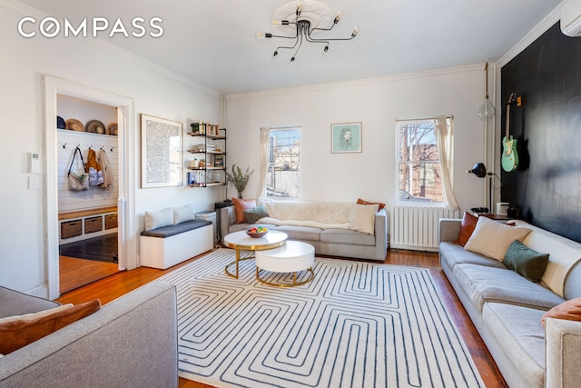 living room with a notable chandelier, crown molding, radiator, wood finished floors, and a wall mounted air conditioner