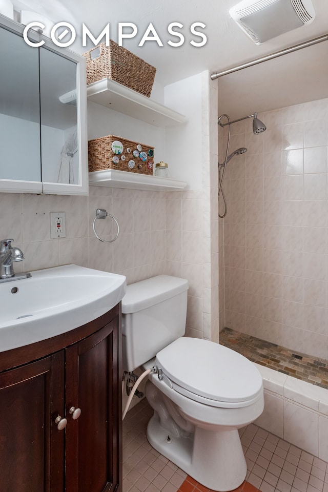 bathroom with toilet, tile patterned floors, a tile shower, and vanity