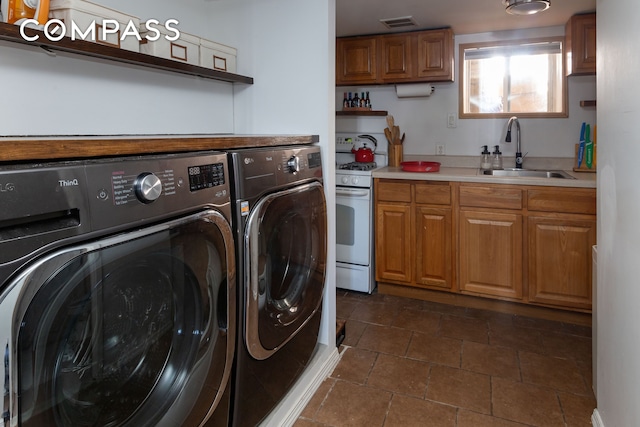 laundry room with washing machine and dryer, visible vents, and a sink