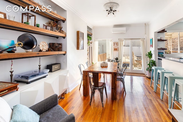 dining space with a wall unit AC, light wood-style floors, ornamental molding, and a wealth of natural light