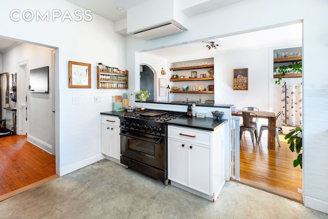 kitchen featuring a wall mounted air conditioner, white cabinetry, black range with gas stovetop, open shelves, and dark countertops