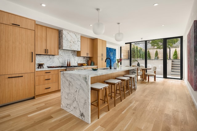 126 Washington Ave, New York City, NY 11205 - kitchen with a wall of windows, a sink, backsplash, a kitchen bar, and light wood-style floors
