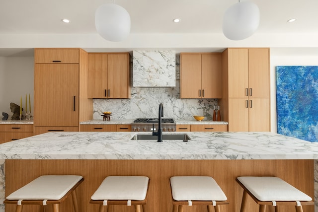 126 Washington Ave, New York City, NY 11205 - kitchen with tasteful backsplash, a sink, a breakfast bar area, wall chimney exhaust hood, and light stone countertops