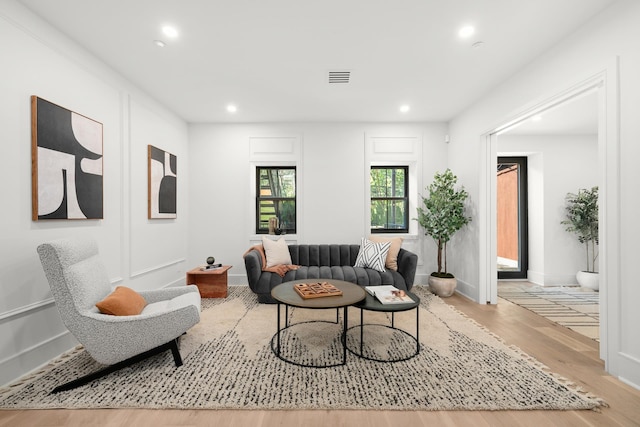 living area with baseboards, wood finished floors, visible vents, and recessed lighting