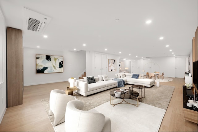 living area with stairs, light wood-type flooring, and recessed lighting