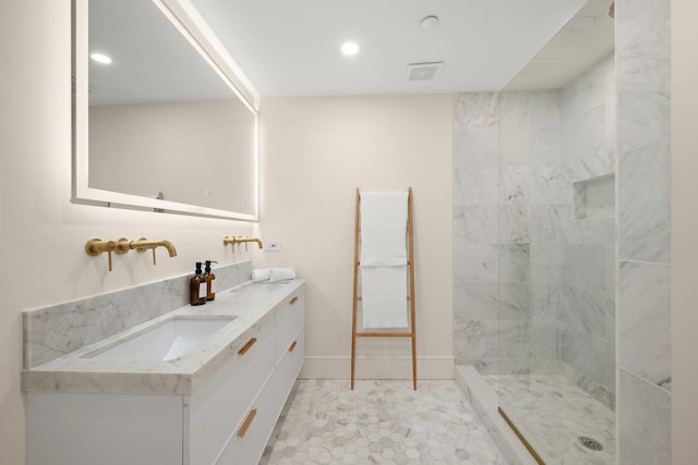 full bath with double vanity, visible vents, baseboards, tiled shower, and a sink