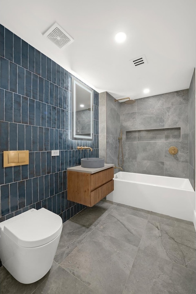 full bathroom with visible vents, toilet, vanity, tile walls, and shower / bathing tub combination