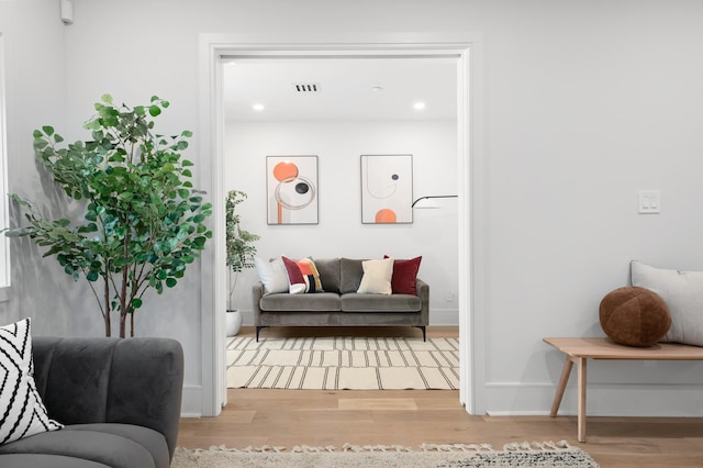 living area with baseboards, visible vents, and wood finished floors