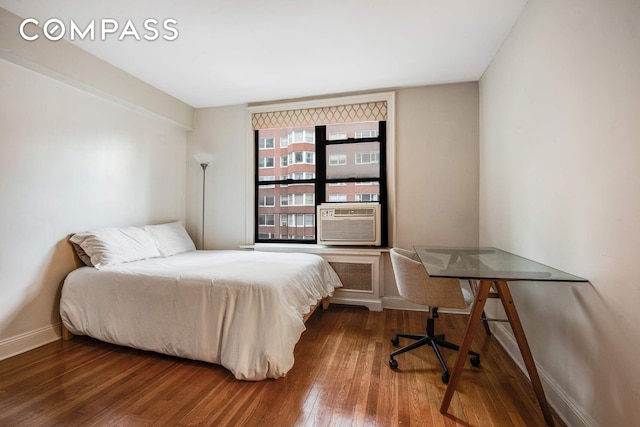 bedroom with cooling unit, baseboards, and hardwood / wood-style floors