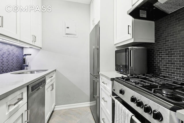 kitchen featuring light tile patterned floors, stainless steel appliances, light countertops, under cabinet range hood, and a sink