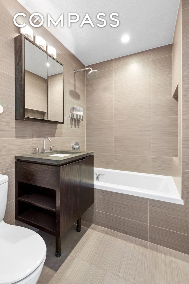 full bathroom featuring vanity, tile patterned flooring, tile walls, toilet, and tiled shower / bath