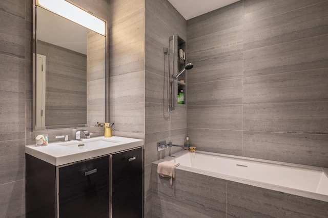 full bath with tiled shower / bath, vanity, and tile walls