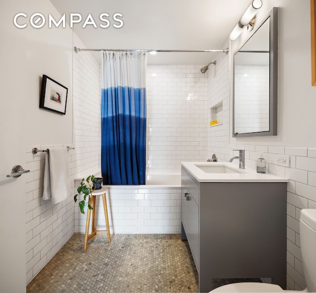 bathroom featuring toilet, tile patterned floors, tiled shower / bath combo, vanity, and tile walls