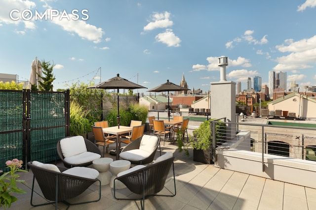 view of patio / terrace featuring a view of city, fence, and outdoor dining space