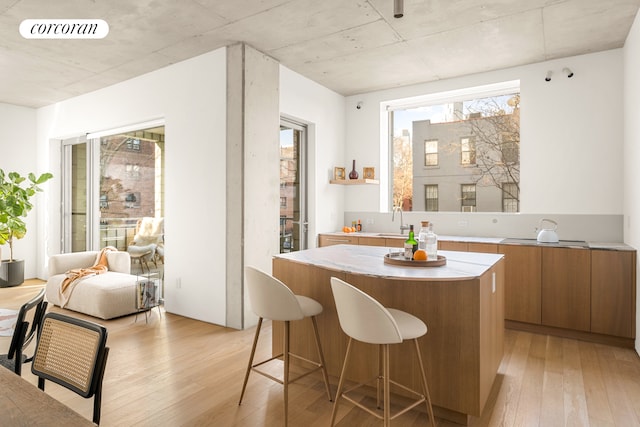 interior space featuring brown cabinets, light wood-style flooring, a center island, and a sink