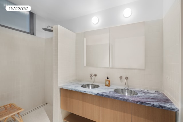 bathroom featuring double vanity, walk in shower, tasteful backsplash, and a sink